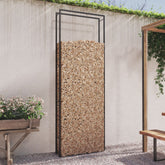 Matt black steel firewood rack holding stacked logs against a white wall in an outdoor patio setting.